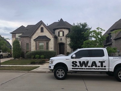 SWAT roofing white truck parked outside a house