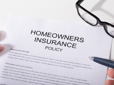 homeowners insurance policy paperwork with glasses and a pen