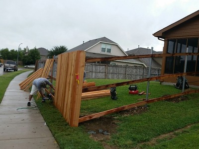 man building a fence in green grass 