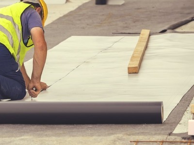 man with yellow vest on a roof cutting some protection for the roof